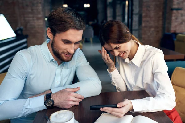 business man and woman sitting in a cafe having a snack rest communication telephone in hands
