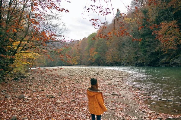 Femme dans une veste jaune près de la rivière montagnes nature promenade — Photo