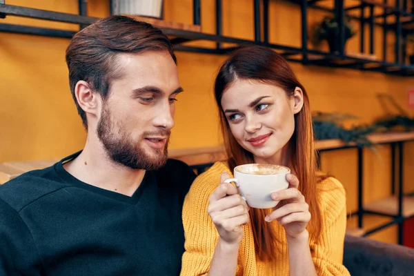 Egy nő szerelmes egy csésze kávéba és egy boldog férfi egy asztalnál egy kávézó belsejében barátok kommunikáció — Stock Fotó