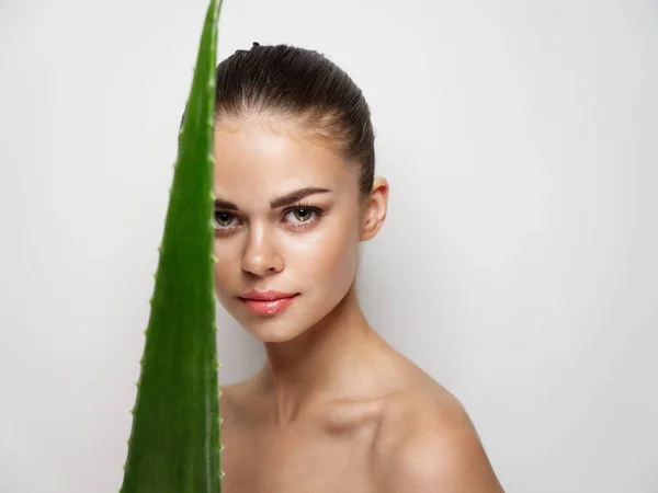 Mulher confiante com folha de aloés no fundo claro e ombros nus pele clara — Fotografia de Stock