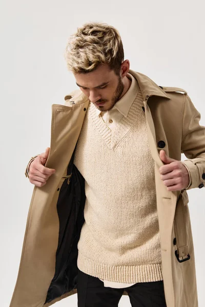 Um homem loiro com um casaco e uma camisa com um modelo de barba de camisola na mão — Fotografia de Stock