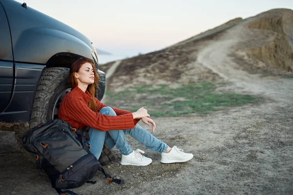 Mulher turista nas montanhas na natureza senta-se perto do carro e montanhas estrada paisagem — Fotografia de Stock