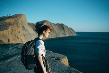 Sırt çantalı kadın deniz kenarındaki dağlarda seyahat ediyor.