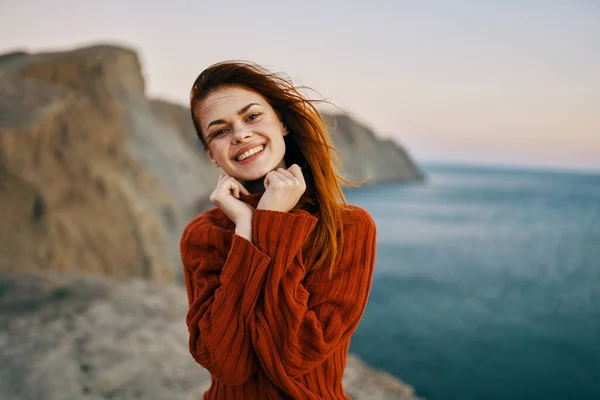 Donna in un maglione gesti con le mani all'aperto in montagna vicino al mare — Foto Stock