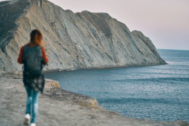 Kadın deniz kenarındaki dağlarda ve kayalar arka planda. Temiz hava.