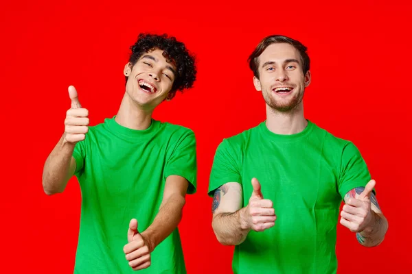 녹색 티셔츠를 입은 두 친구가 손에 감정을 가지고 몸짓을 한다 — 스톡 사진