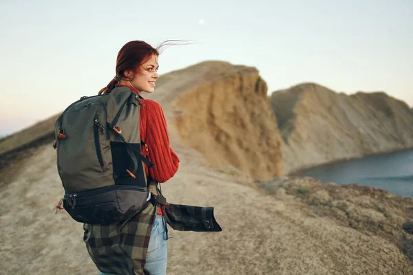 Schöne Frau in den Bergen in der Natur mit einem Rucksack auf dem Rücken in Meeresnähe — Stockfoto