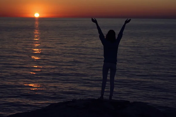 Σιλουέτα ενός άνδρα με τα χέρια ψηλά στην παραλία και το ηλιοβασίλεμα στο παρασκήνιο — Φωτογραφία Αρχείου