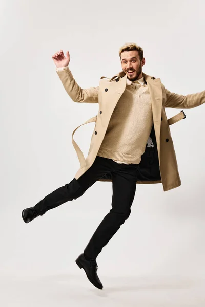 Веселый человек в пальто осенний стиль движения эмоции легкий фон — стоковое фото