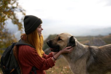Açık havada gezen bir köpeğin yanında neşeli bir kadın.
