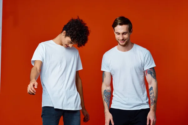 Двоє веселих друзів у футболках, що спілкуються емоціями червоний фон — стокове фото