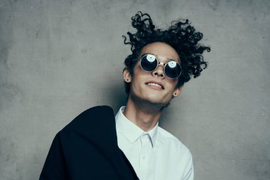 Güneş gözlüklü, kıvırcık saçlı, ceketli adam.