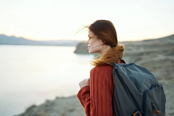 Donna viaggia in montagna nella natura vicino al mare con uno zaino sulla schiena — Foto Stock