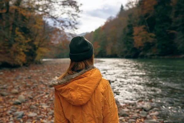 Vrouw wandelaar bewondert de natuur in de bergen herfst rivier — Stockfoto