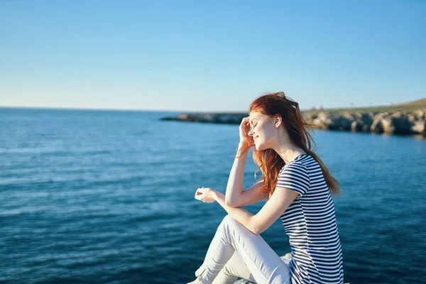 一个女人在靠近大海的岩石上，在高山的夕阳下夏天 — 图库照片