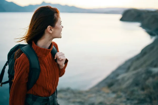 Viaggiatore felice in un maglione e con uno zaino guardare il mare in lontananza e montagne natura aria fresca — Foto Stock