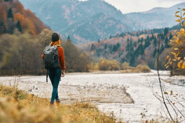 Femme sur la rive de la rivière dans les montagnes dans la forêt d'automne dans la nature vue arrière — Photo