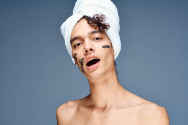 Yüzüne krem sürmüş, omuzları çıplak yakışıklı bir adam.