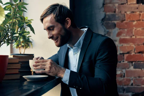 Homem de negócios em um terno sentado em um café trabalho de lazer — Fotografia de Stock