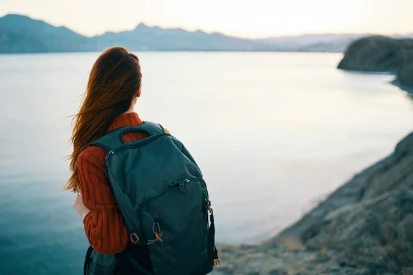 Donna in maglione rosso con zaino e turismo di viaggio mare montagne vista posteriore — Foto Stock