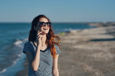 Tişörtlü ve gözlüklü bir kadın portresi. Deniz kenarındaki dağlarda.