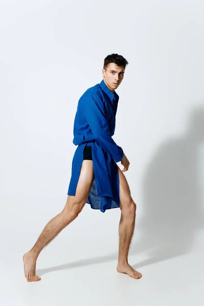 Sexy gay guy in een blauw jurk op een licht achtergrond in volledige groei draaide naar de zijkant — Stockfoto