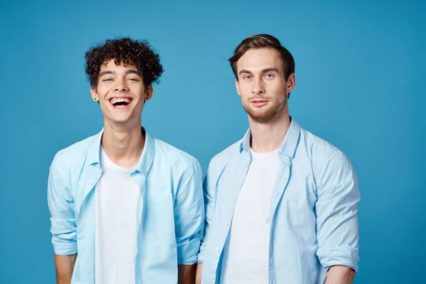 같은 셔츠를 입고 있는 두 친구와 푸른 배경에 손을 뻗고 있는 티셔츠 — 스톡 사진