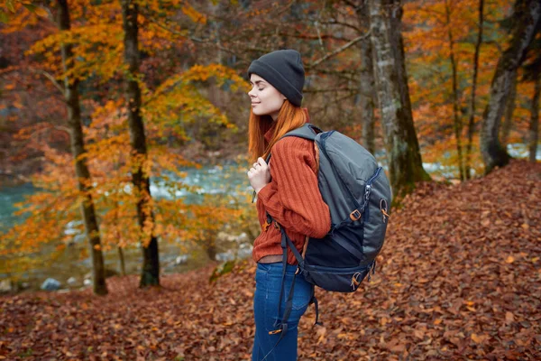 Frau mit Rucksack wandert im Herbstpark in Flussnähe in Naturseitensicht — Stockfoto