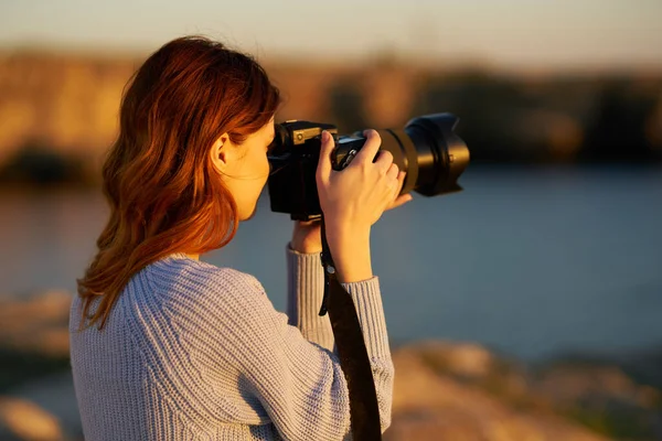 Frau mit professioneller Kamera bei Sonnenuntergang am Meer — Stockfoto