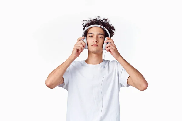 Τύπος με σγουρά μαλλιά και ακουστικά λευκό t-shirt φως φόντο close-up περικοπή — Φωτογραφία Αρχείου