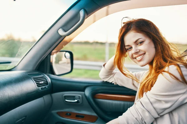 Mulher feliz no suéter dirigindo no assento dianteiro de um carro modelo de design de interiores limpo — Fotografia de Stock