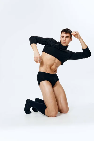 Homem sexy com um torso bombeado em shorts e em meias pretas posando em um fundo leve — Fotografia de Stock