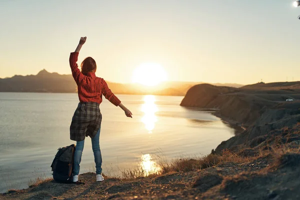 Woman tourist with hands raised up horizon sunset back view — Stock Photo, Image