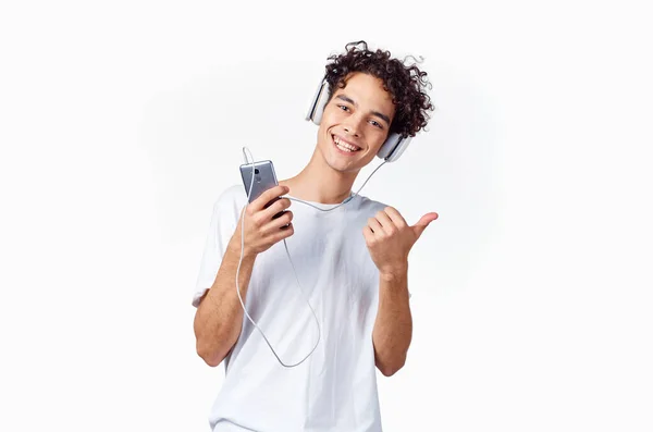 Chico con el pelo rizado y auriculares blanco camiseta fondo claro recortado — Foto de Stock