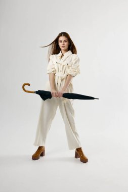 Kadın tulumlu, elinde şemsiyeyle stüdyo yaşam tarzını geliştiriyor.