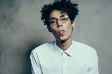 Gözlüklü, kıvırcık saçlı, beyaz gömlekli, mutlu bir adamın portresi.