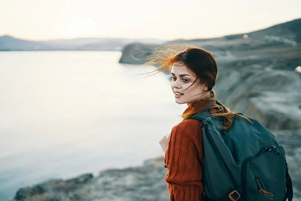 Жінка з рюкзаком на природі в горах біля моря на заході сонця — стокове фото