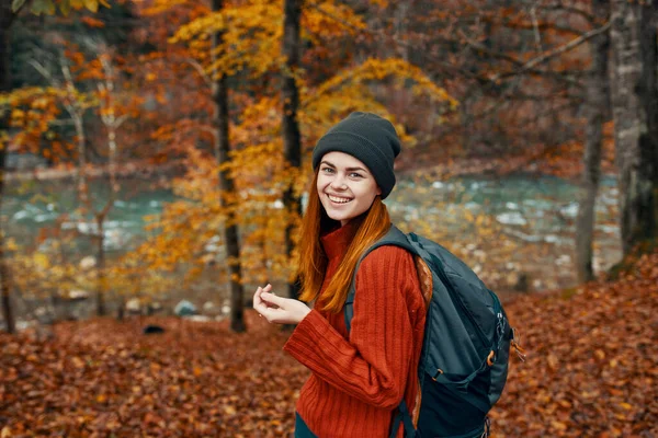 Wesoła kobieta podróżuje w jesiennym lesie w przyrodzie w pobliżu rzeki i wysokie drzewa w tle — Zdjęcie stockowe