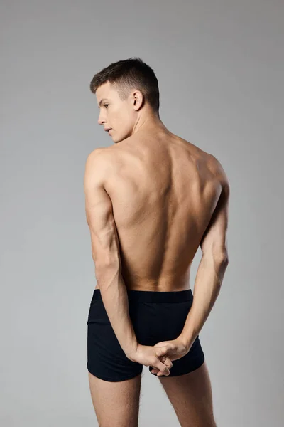 Hombre guapo con bombeo hasta los músculos del brazo desnuda espalda gris fondo modelo — Foto de Stock