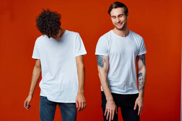 Due amici allegri in t-shirt comunicare emozioni sfondo rosso — Foto Stock