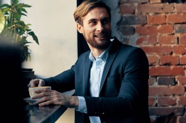 Takım elbiseli bir iş adamı kafeteryada oturmuş kahvaltı yapıyor.