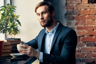 Bir kafede oturan takım elbiseli bir adam. Bir fincan kahve. Profesyonel eğlence.