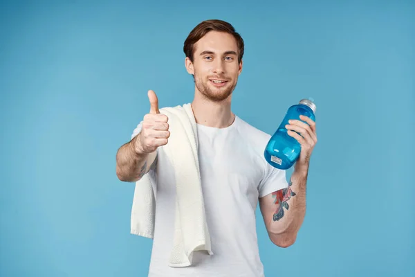 Sporty uomo mostrando pollice in su bottiglia d'acqua asciugamano sulla spalla ritagliato vista sfondo blu — Foto Stock