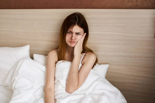 woman woke up early in the morning and touch her face with her hands under the covers in bed