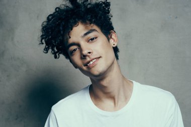 Tişörtlü, kıvırcık saçlı, yakın plan kumaşlı çekici bir adamın portresi.