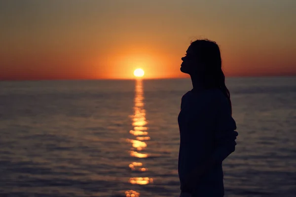 Mulher ao pôr do sol perto do mar com uma câmera na mão — Fotografia de Stock