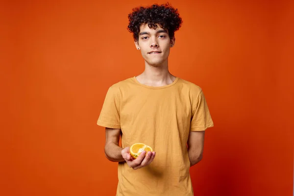손에 붉은 색 과일을 들고 있는 곱슬머리 오렌지를 가진 남자 — 스톡 사진