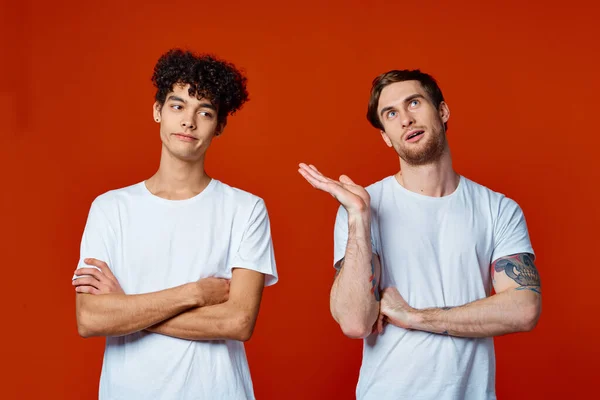 흰색 티셔츠 건축 팀에서 일하는 두 친구가 빨간 배경에 감정을 느낀다 — 스톡 사진