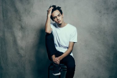 Sandalye stüdyosunda oturan kıvırcık saçlı adam.