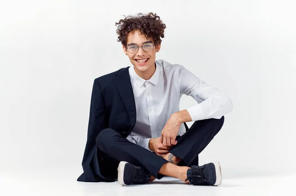 Joven elegante con el pelo rizado y en un traje clásico sobre un fondo claro —  Fotos de Stock